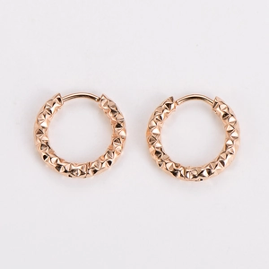 Detail of rose gold hoop earrings with faceted diamond texture on white background