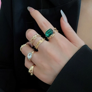 Close-up of gold geometric rings with green gemstone and zircons on a model's hand