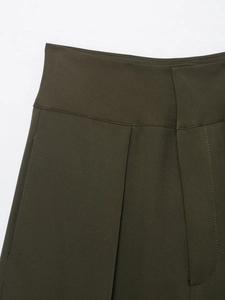 Detail of high waisted olive pleated trousers showing the fine woven texture and stitching