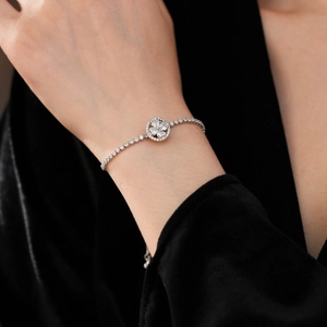 Detailed view of rotating zircon clover bracelet on a wrist with silver chain and stones