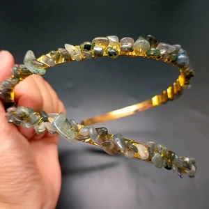 Close-up of handmade gold headband with green and grey natural crystal stones