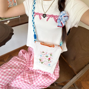 Détail du sac en tissu oxford blanc avec broderies florales et bandoulière tressée