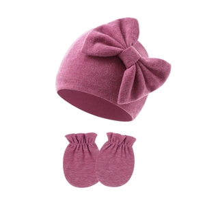 Detailed knit texture of dark pink infant hat and mittens set with large bow accent