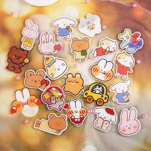 Flat lay of cute acrylic cartoon bear and rabbit patches on yellow textured fabric
