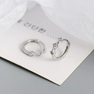 Macro shot of silver diamond rhombus hoop earrings with sparkling cubic zirconia inlay