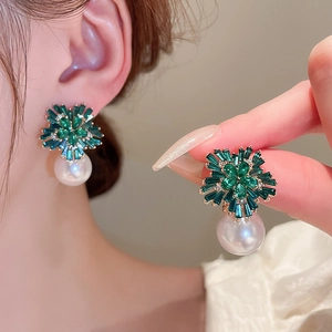 Close-up of green zircon flower earrings with white pearl drop on female model ear