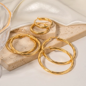 Golden 18K stainless steel cable twist hoop earrings in three sizes on stone base