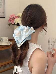 Close-up of starry sky pattern hair tie with long ribbons and pearl charm on model