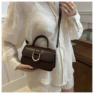 Dettaglio di una piccola borsa quadrata marrone vintage con fibbia a U dorata e manico