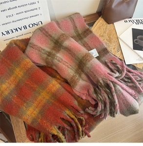 Detail of warm checkered scarves with tassels in pink and orange on a wooden table