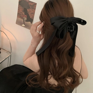 Detail of elegant black ribbon bow hair claw clip with long streamers on model