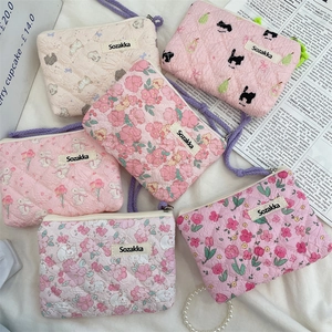 Close-up of quilted floral cotton pouches with zipper and purple braided handles