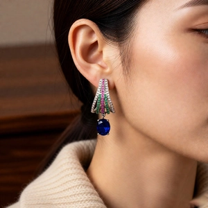 Detailed view of vintage-style oval sapphire pendant earrings worn by a model in warm light