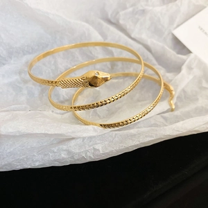 Detailed close-up of golden snake-shaped bracelet with elegant diamond pattern engraving