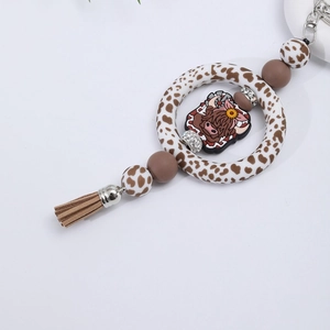 Detail of silicone beaded ring keychain with highland cow pendant and brown tassel