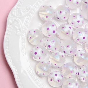 Vue macro de perles en acrylique 16mm peintes ciel étoilé avec motifs floraux
