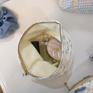 Top view of floral cotton makeup bag interior with cosmetics on a white surface