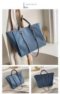 Detalle de bolso tipo cubo en denim azul con asas dobles y correa de cadena metal