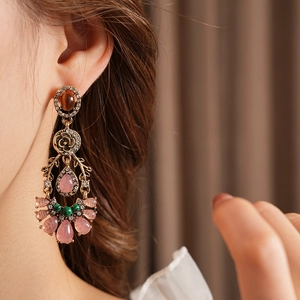Macro shot of vintage rhinestone flower earrings with pink and green stones on a model