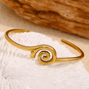 Macro shot of 18K gold plated spiral cuff bracelet on a white textured coral base