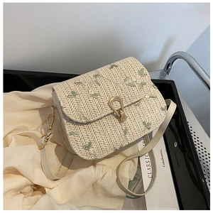 Detail of beige straw bag with green flower embroidery and golden twist-lock closure
