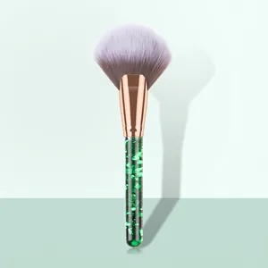 Macro view of fan makeup brush with lavender bristles and green glitter liquid handle