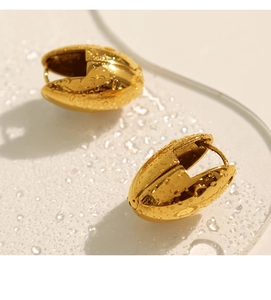 Detailansicht der polierten goldenen Tropfenohrringe auf einer sauberen Wassertropfenoberfläche