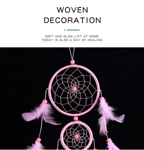 Detail of pink woven dreamcatcher featuring intricate netting, beads and soft feathers