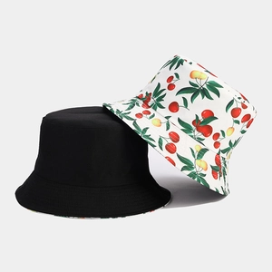 Close-up of a minimalist black cotton bucket hat and a white cherry print sun hat set