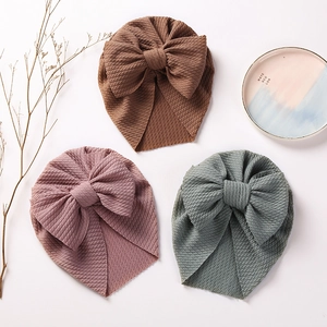 Detailed knit texture of baby headwraps with large bows in brown, purple, and green colors