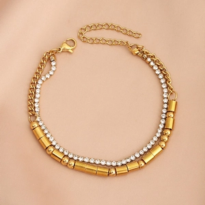 Close-up of golden double-layer bracelet with clear rhinestones and cylinder chain on silk