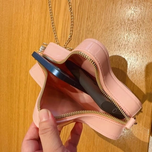 Pink heart-shaped chain bag interior showing storage capacity for a smartphone