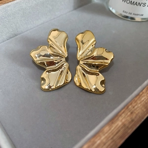 Detail of golden flower petal earrings with wrinkled texture on gray velvet display