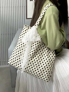Close-up of retro polka dot canvas tote bag featuring a delicate white lace bow detail