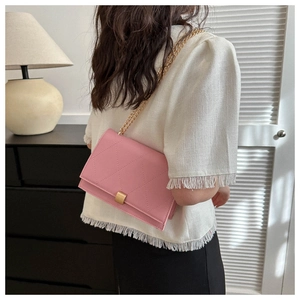 Pink quilted shoulder bag detail with gold chain strap and metal clasp on a model