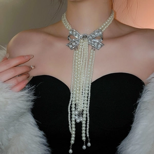 Détail d'un collier de perles double épaisseur avec gros nœud en strass et longs pompons