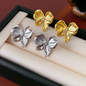Elegant bow-knot stud earrings in gold and silver finish with crystal center and matte texture
