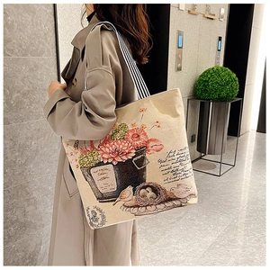 Detail of artistic floral and bird nest print on beige canvas shoulder bag