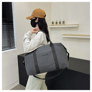 Dark grey large travel bag shown on model with adjustable shoulder strap details