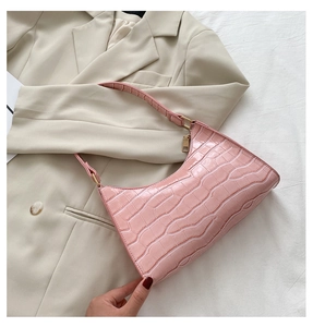 Detailed view of pink crocodile pattern baguette bag on a stylish beige blazer