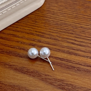 Close-up of elegant white pearl stud earrings with S925 silver hallmarks on the pins