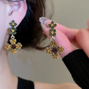 Detailed macro view showing vintage gold flower earrings with amber crystals and red gems