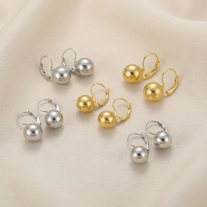 Close-up of polished gold and silver ball earrings with lever-back closures on silk