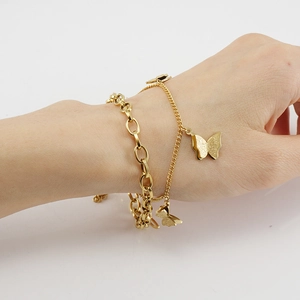 Close-up of 18K gold stainless steel double chain bracelet with matte butterfly charm