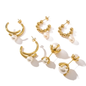Three pairs of vintage gold titanium steel C-shape earrings with pearls on white background