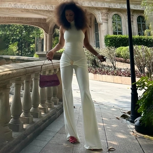 White sleeveless halter neck jumpsuit with gold buckle detail and wide leg pants