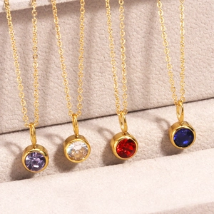 Detailed shot of four gold necklaces with purple, clear, red, and blue birthstone pendants