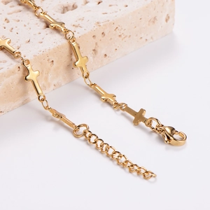Adjustable golden stainless steel bracelet with cross charms on a textured stone base