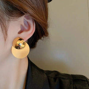 Dettaglio degli orecchini geometrici in oro con finitura in metallo spazzolato