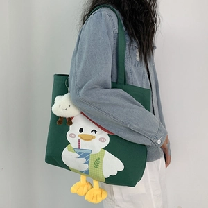 Detail of dark green canvas tote featuring cartoon duck embroidery and plush cloud charm